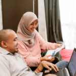 young muslim couple using laptop to pay bill at home